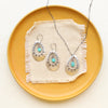 The pakal teardrop cutout turquoise long necklace styled with the matching earrings on a yellow plate and tan linen