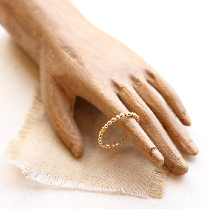 14k gold fill beaded stacking ring styled with a wooden hand and tan linen