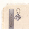 A talara winter sun earring next to a ruler for size reference