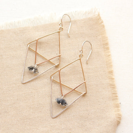 the triple layered triangle mixed metal herkimer diamond earrings styled on tan linen