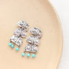 The pakal trio turquoise dangle post earrings styled on a tan plate