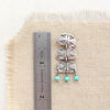 A pakal trio turquoise dangle post earring next to a ruler for size reference
