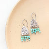 The pakal arch turquoise fringe earrings styled on a tan plate