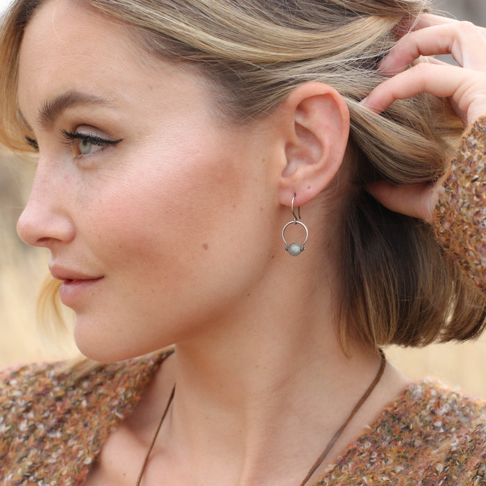 A model wearing the pinned labradorite la cloche earrings