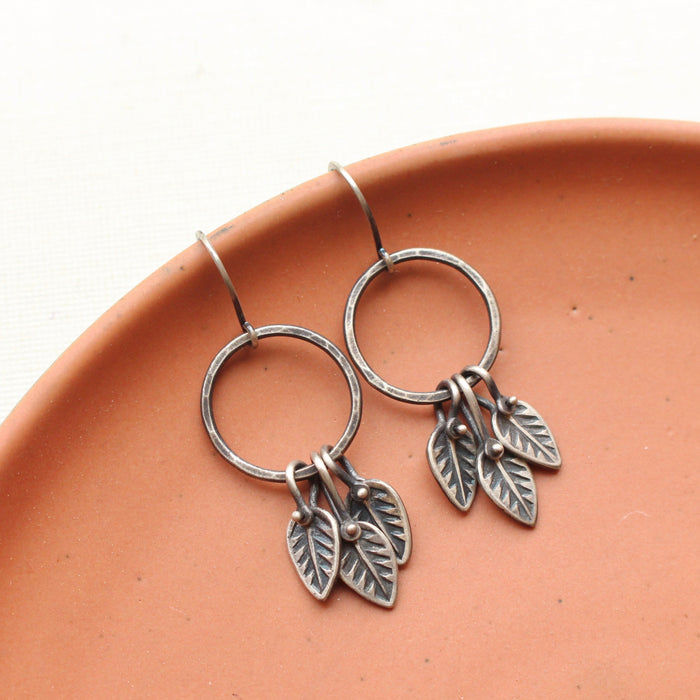 The stamped leaf trio hoop earrings styled on a red plate