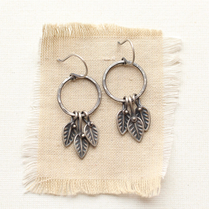 The stamped leaf trio hoop earrings styled on tan linen