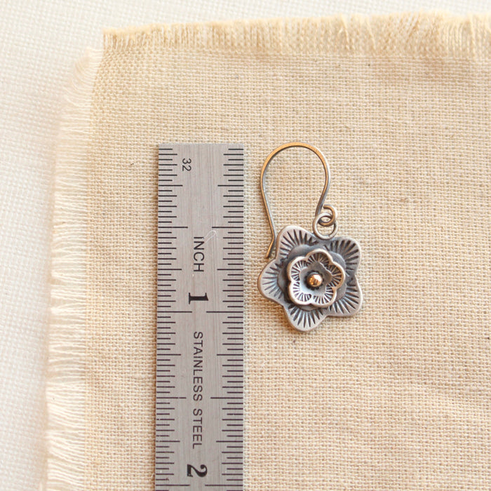 A layered cactus flower mixed metal earring next to a ruler for size reference