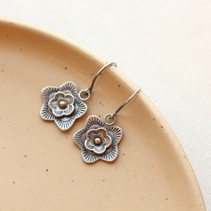 The layered cactus flower with gold center earrings styled on a tan plate