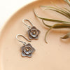 The layered cactus flower gold dot earrings styled on a tan plate with an airplant
