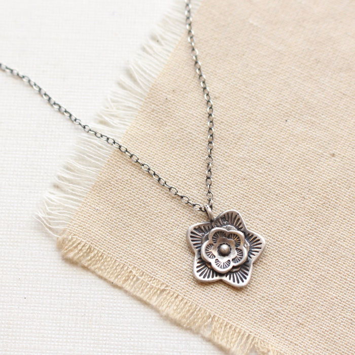 The silver layered cactus flower necklace styled on tan linen