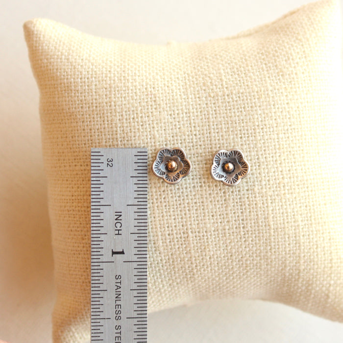The mini cactus flower gold dot earrings next to a ruler for size reference