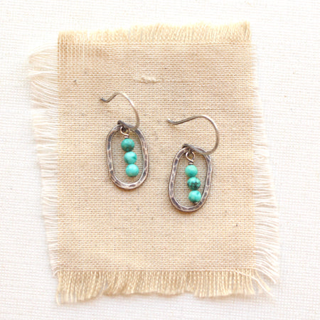 The southwest inspired stacked mini turquoise silver hoop earrings styled on tan linen
