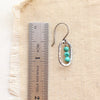 A stacked mini turquoise silver hoop earring next to a ruler for size reference