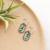The southwest inspired stacked mini turquoise silver hoop earrings styled on a tan plate with an airplant