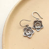 The silver layered cactus flower earrings styled on a tan plate