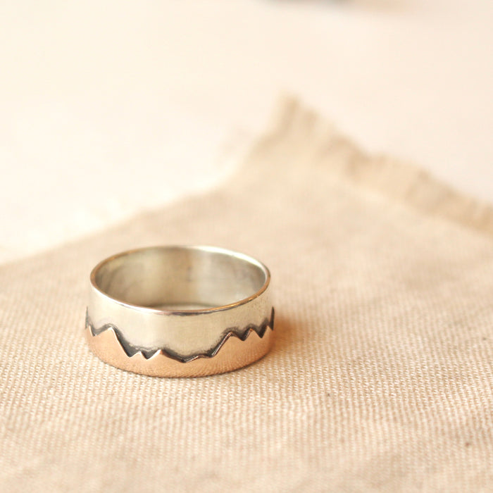Polished bronze and silver mountain ring styled on tan linen
