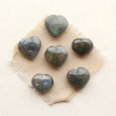 six green and blue labradorite heart stones styled on tan linen