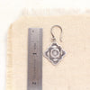 A layered talara sun earring next to a ruler for size reference