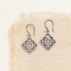 The stamped silver layered talara sun earrings styled on tan linen
