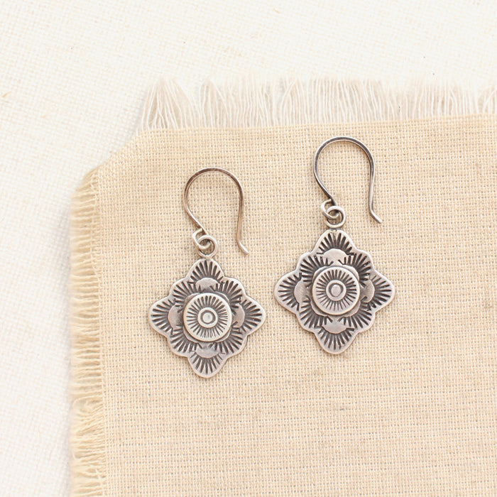 The stamped silver layered talara sun earrings styled on tan linen