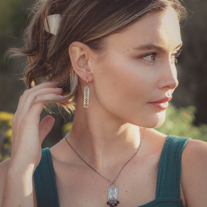 A model wearing the stamped silver sun bar earrings