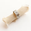 The arabesque stamped band ring styled on tan linen