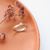 The del mar textured white gold band and natural diamond ring styled on a red plate with dried flowers