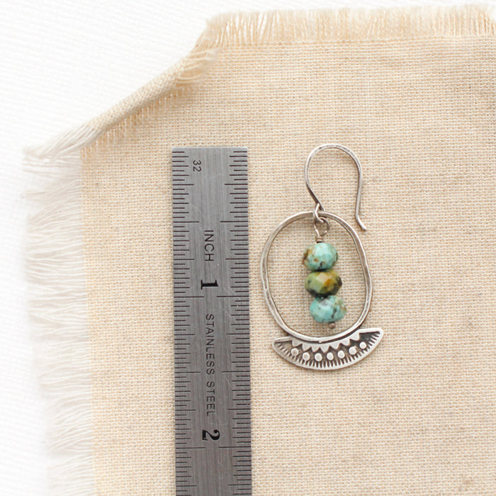 An asmi oval hoop turquoise earring next to a ruler for size reference