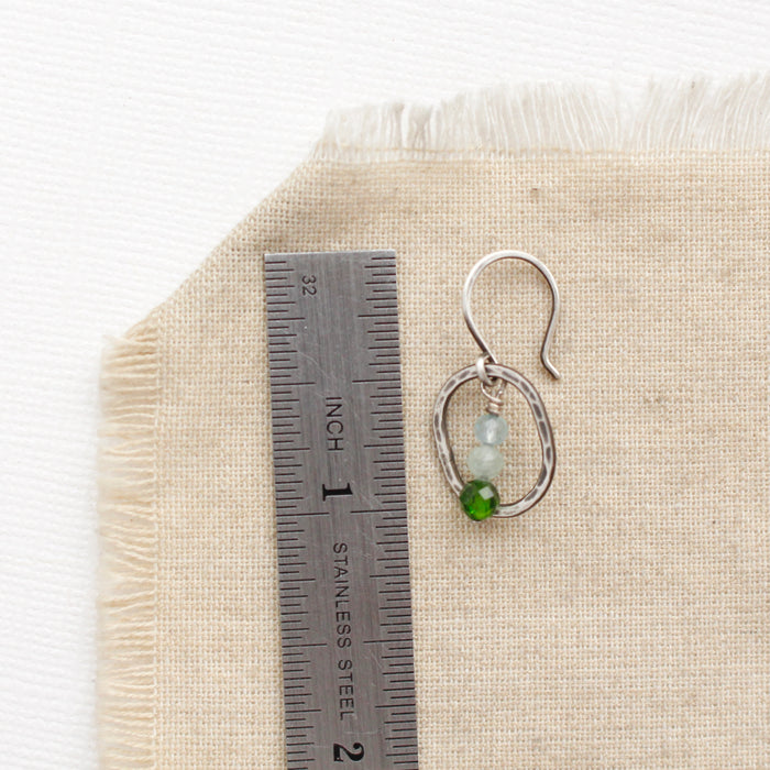 A stacked emerald isle mini hoop earring next to a ruler for size reference