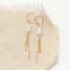 the stacked herkimer diamond gold tassel earrings styled on tan linen