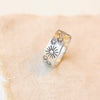 Hand stamped silver ring with small and large sun designs styled on tan linen.