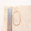 An organic gold hoop earring next to a ruler for size reference