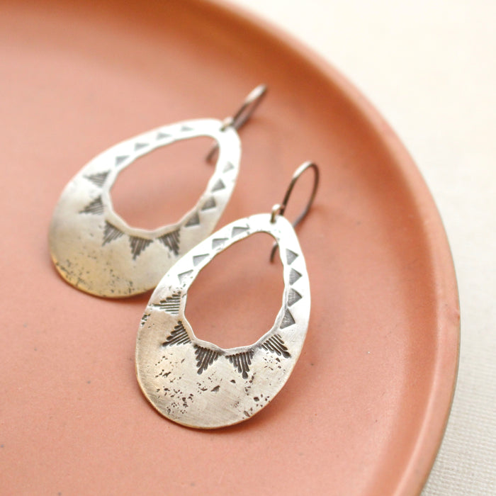 The southwest inspired pakal teardrop cutout earrings styled on a red plate