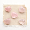 5 heart shaped rose quartz stones styled on tan linen.