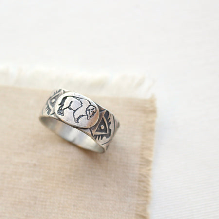 Stamped silver buffalo ring styled on tan linen