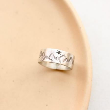 Stamped Mountains and Stars Silver Band Ring Styled on Tan Plate.