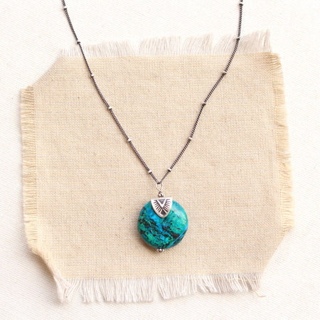 The capped chrysocolla necklace styled on tan linen