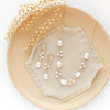 The gold wrapped pearl bud vine earrings styled on a tan plate with the matching necklace