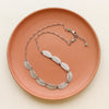 The asmi full collar necklace styled on a red plate to show the adjustable chain closure