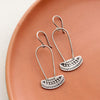 The asmi silver long loop earrings styled on a red plate