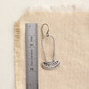 An asmi long loop earring next to a ruler for size reference