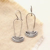 The asmi silver long loop earrings styled on tan linen