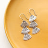 The asmi trio triangle long earrings styled on a yellow plate