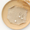 The bright silver perfect pearl necklace styled on a tan plate with the matching earrings