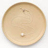 The bright silver perfect pearl necklace styled on a tan plate to show the adjustable lobster clasp closure