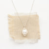 The bright silver perfect pearl necklace styled on tan linen