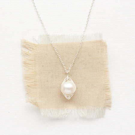 The bright silver perfect pearl necklace styled on tan linen