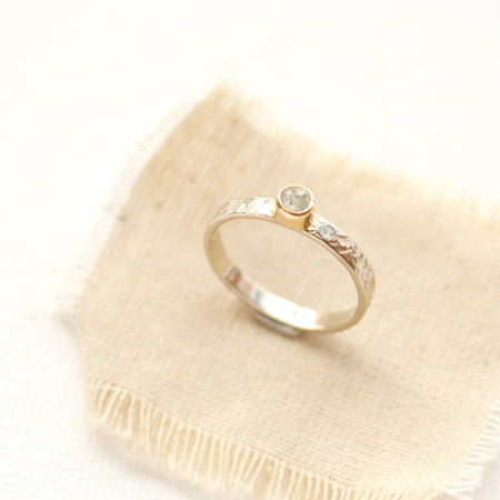 The 14k white and yellow gold & natural diamond ring styled on tan linen