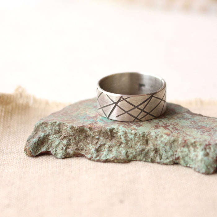 The embrace the chaos stamped band ring styled on a stone and tan linen