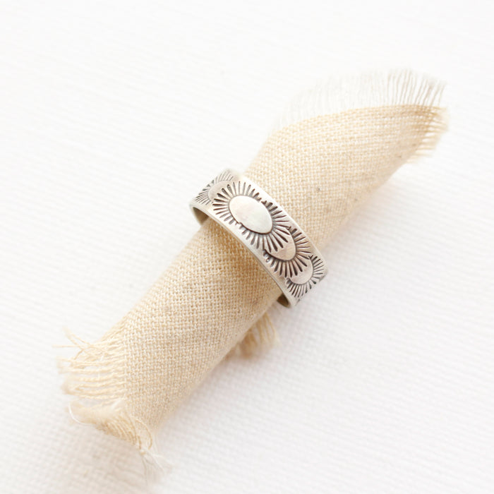 The ever expanding stamped silver band ring styled on a roll of tan linen